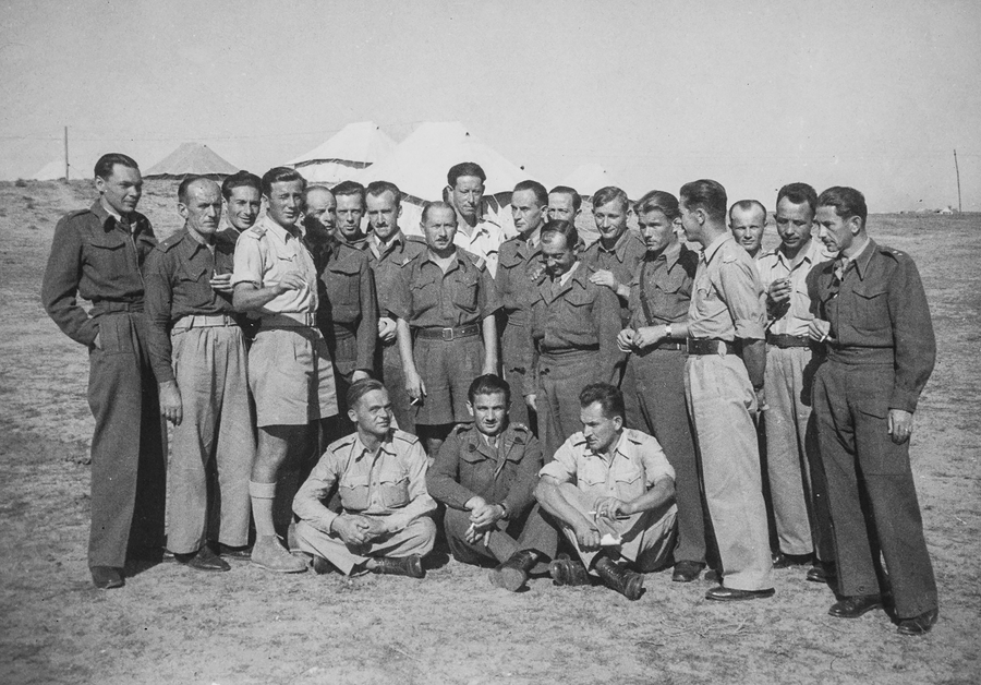 Grupa polskich oficerów i żołnierzy na tle namiotów wojskowych. Ubrani są w battledress-y oraz koszule tropikalne typu brytyjskiego. Pierwszy z prawej por. Władysław Jaksan. Zdjęcie wykonane prawdopodobnie w Iraku, po 3 maja 1943 r.