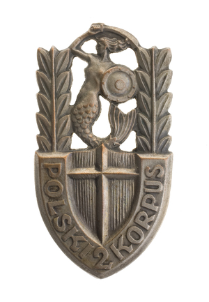 Odznaka pamiątkowa 2 Korpusu Polskiego, którą 28 września 1946 r. otrzymał por. Władysław Jaksan. (W górnej części syrenka z szablą i wieńce laurowe, na dole krzyż i napis: Polski 2 Korpus.)