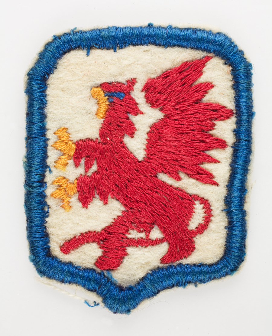 Noszona przez por. Władysława Jaksana odznaka rozpoznawcza 7 Zapasowej Dywizji Piechoty 2 Korpusu Polskiego (Czerwony gryf na białym polu).