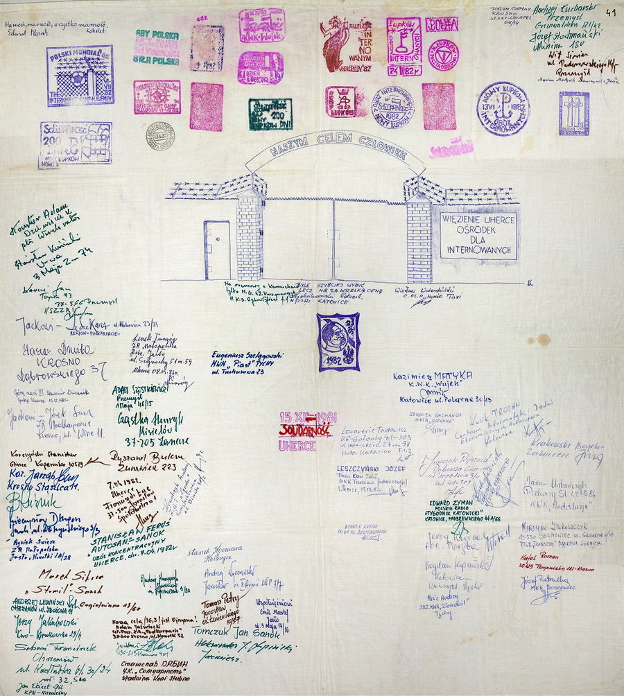 Zdjęcie 031. Materiał bawełniany (prawdopodobnie fragment białego prześcieradła) z odciskami pieczętnymi (z napisami: Obóz Internowanych Nowy Łupków i Uherce) i podpisami osób więzionych w obozie dla internowanych w Uhercach w 1982 r.