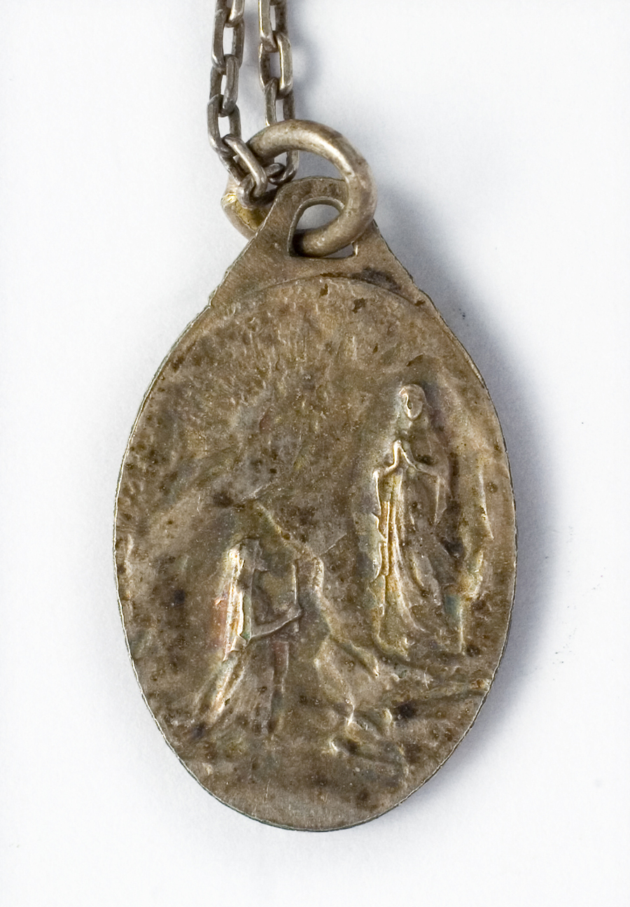 Zdjęcie 023. Srebrny medalik ze sceną objawienia Matki Bożej w Lourdes, należący do Franciszka Cieplika.