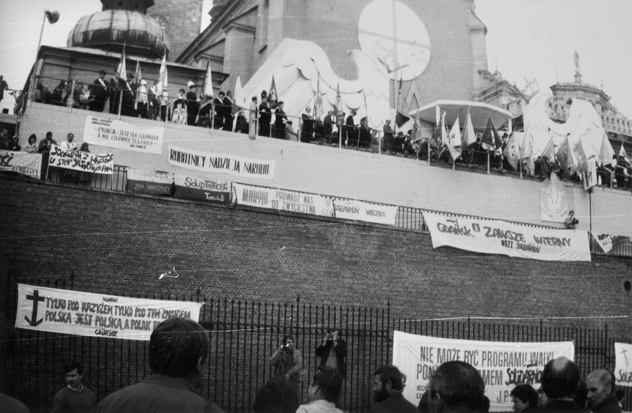 Zdjęcie 008. Zdjęcie wykonane przez nieznanego fotografa podczas pielgrzymki ludzi pracy na Jasną Górę w Częstochowie w dniach od 19 do 20 września 1987 r. Na zdjęciu: transparenty zawieszone przez członków podziemnych struktur NSZZ „S” i przez wiernych na ogrodzeniu i na murach klasztoru jasnogórskiego. Na górze widoczne są poczty sztandarowe NSZZ „S”.
